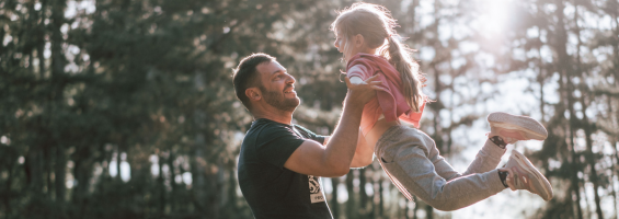 man with beard playing outside with his daughter