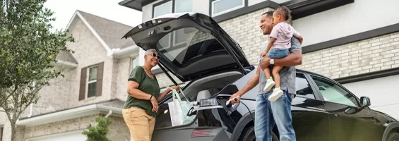 Couple with child outside in the back of their vehicle getting grabbing bags