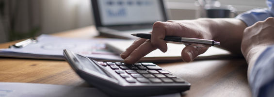 Calculator on a table with fingers pressing buttons 