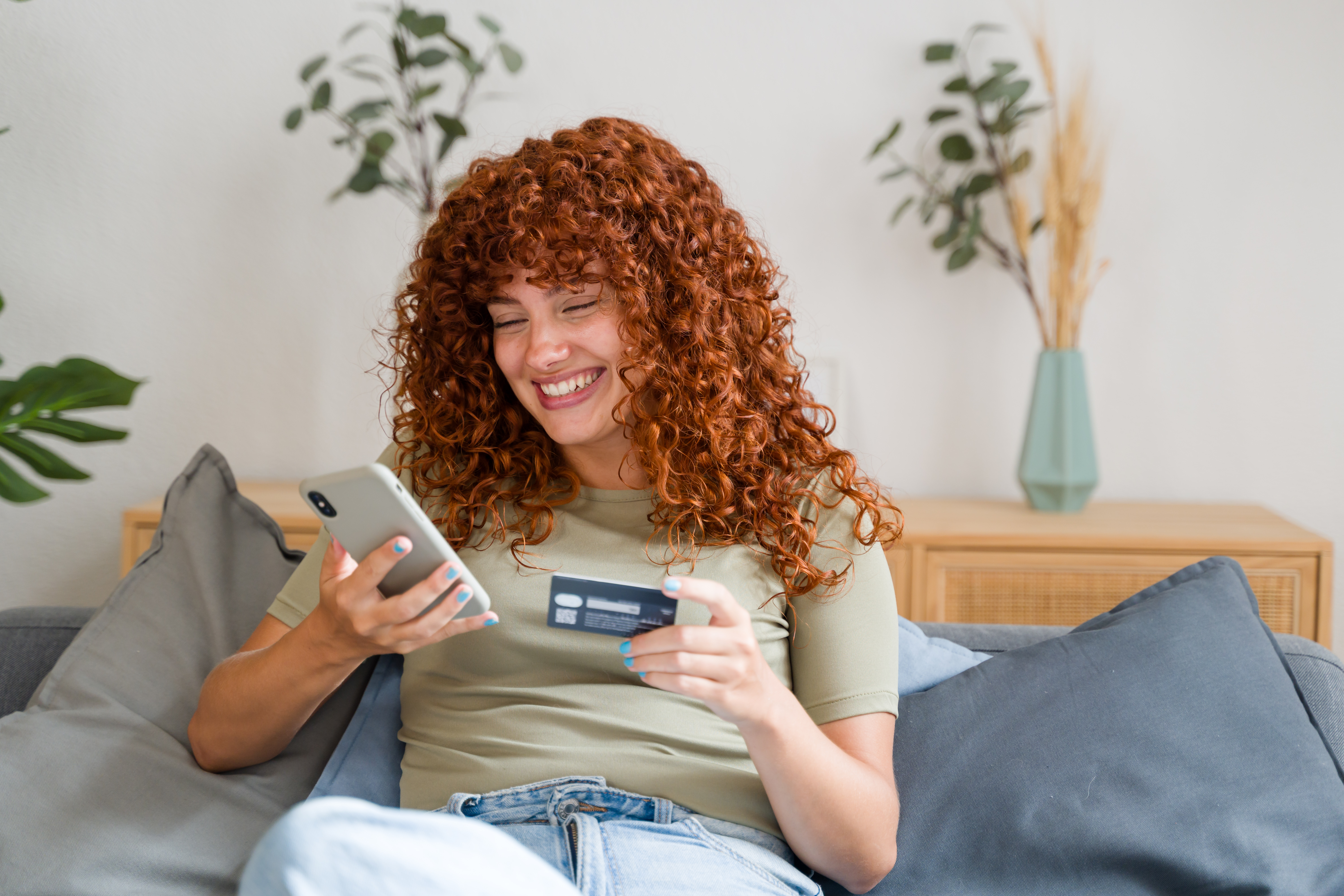girl with curly hair holding phone and card